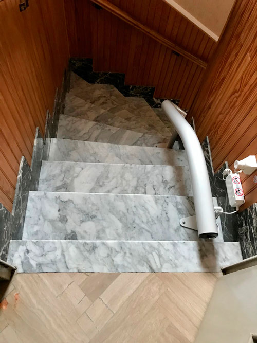 Rail de siège monte escalier fixé sur des marches en marbre.